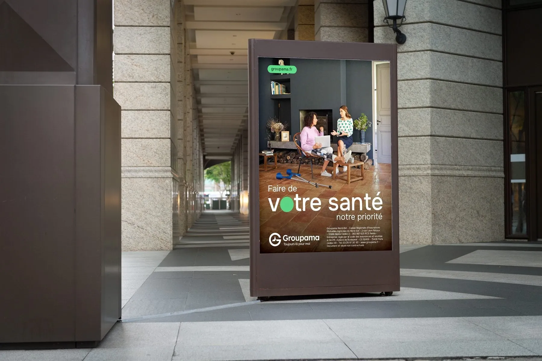 Affiche sucette Groupama « Faire de votre santé notre priorité » sous des arcades en centre-ville