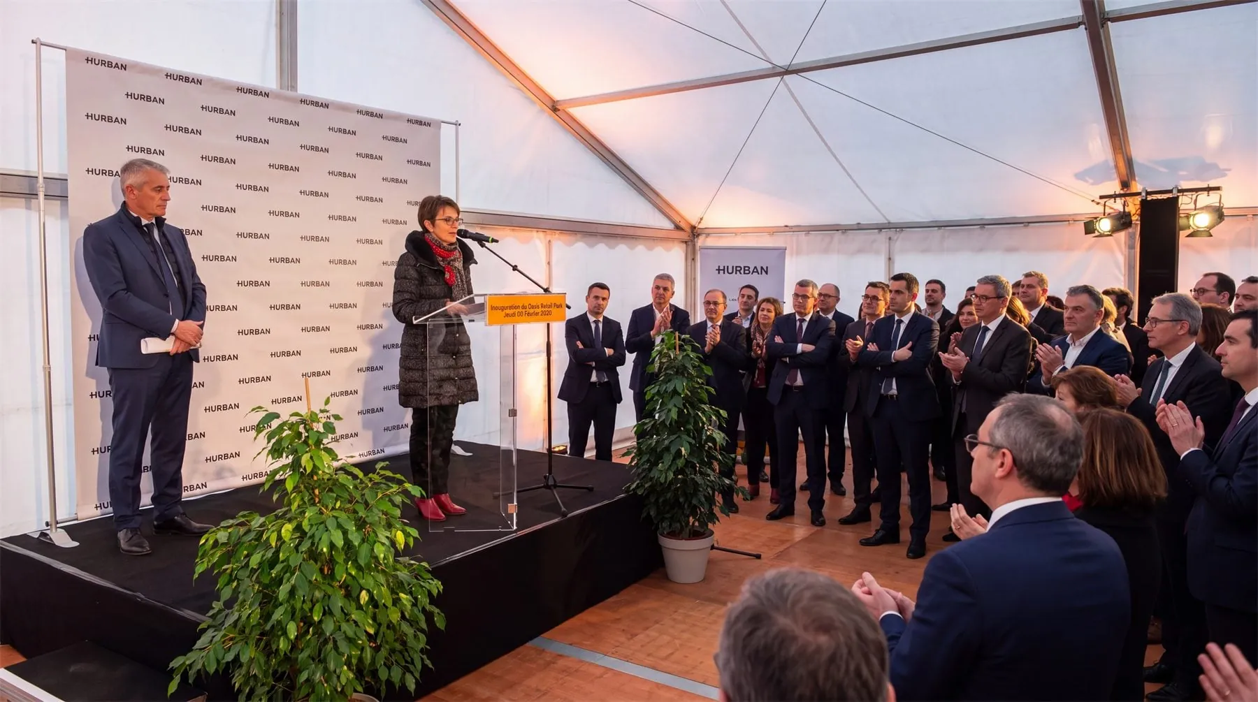 Discours d'inauguration sous chapiteau devant les invités et un mur d'images Hurban