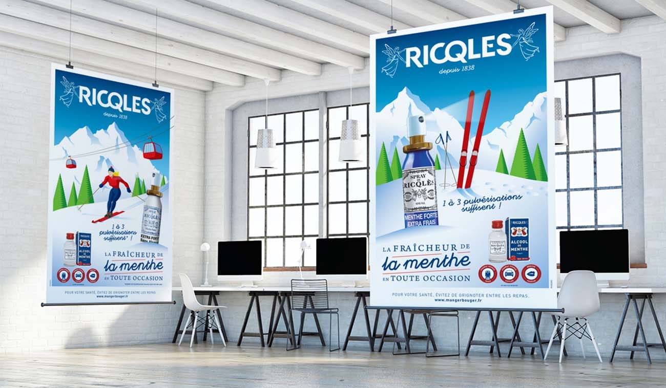 Les deux affiches illustrées Ricqlès, skieuse et skis plantés dans la neige, suspendues dans un atelier lumineux